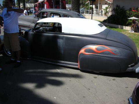 1998 Ford Crown Victoria - Profile of a chopped flat-black custom convertible with a white folding top and orange flame graphics on the rear fender at a show.
