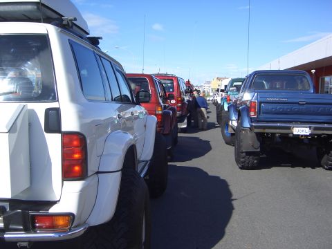 1996 Ford Bronco - Several modified off-road vehicles are parked in a line on a sunny day.