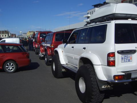 1996 Ford Bronco - Multiple off-road SUVs are parked in a line under a clear blue sky.