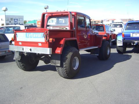 1996 Ford Bronco - A modified red truck with oversized tires is parked in a lot with other vehicles. The side of the truck bed has text that reads Lyfjaval.