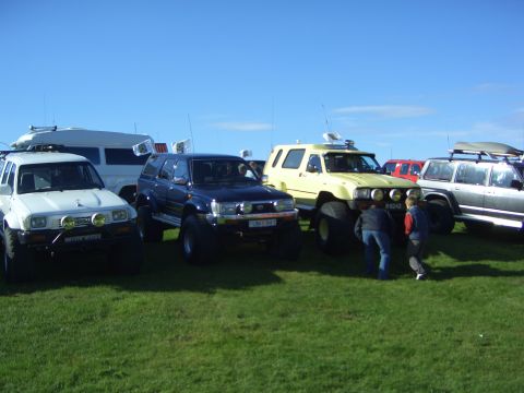 1996 Ford Bronco - A collection of off-road vehicles gathered on a sunny day with clear blue skies.