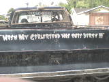 1984 Ford Bronco - A black pickup truck's rear is shown, custom text on the tailgate.