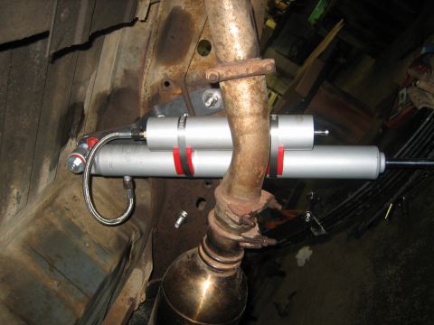 1990 Ford Bronco - Close-up from underneath of a new aluminum-bodied remote-reservoir shock with red anodized rings and a braided stainless hose, mounted to a…