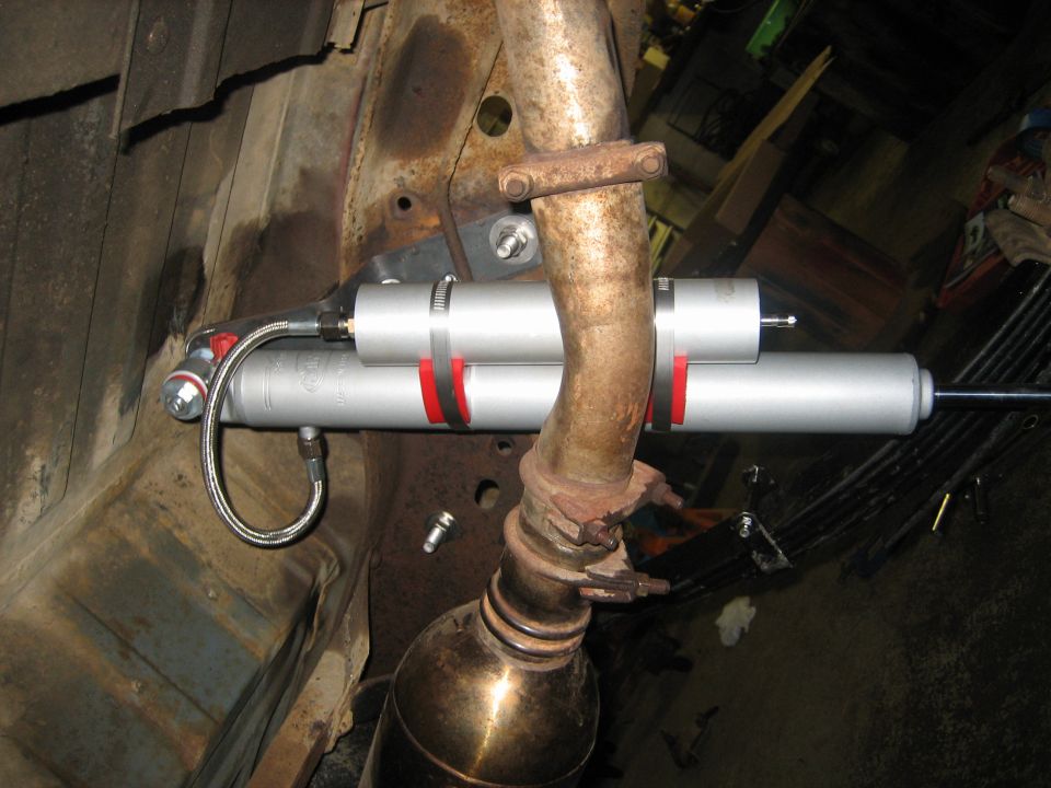 Aluminum remote-reservoir shock with braided hose mounted next to exhaust pipe