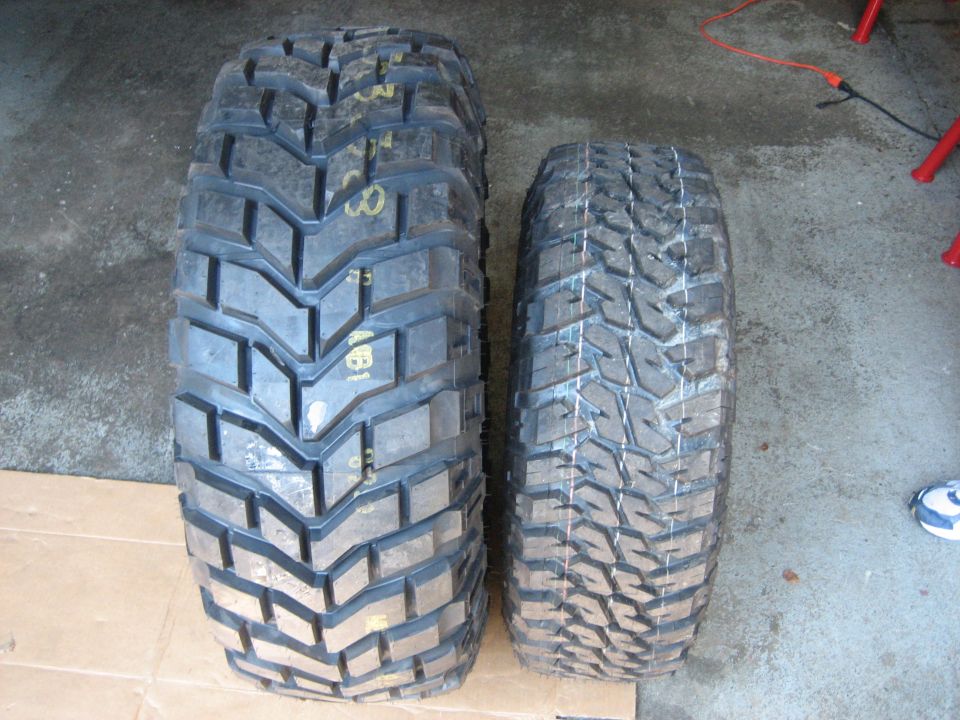 Two off-road tires side by side comparing tread width and lug depth on a garage floor