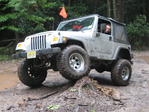 2002 Jeep Wrangler - This Jeep Wrangler is navigating a challenging off-road course with muddy terrain and obstacles.