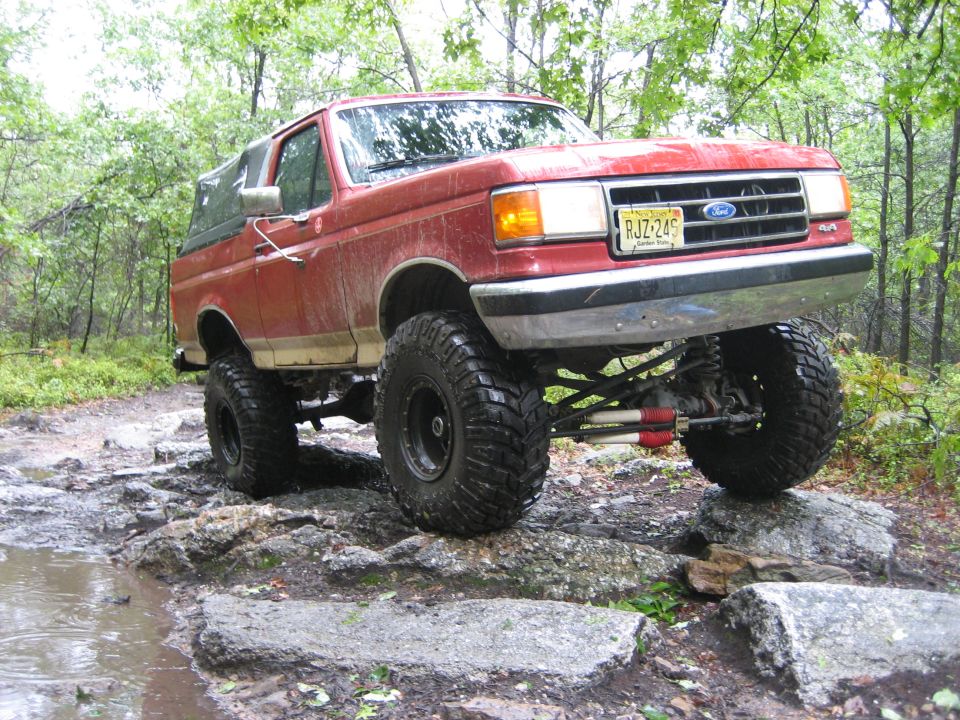 1990 Ford Bronco with large tires navigating rocky terrain