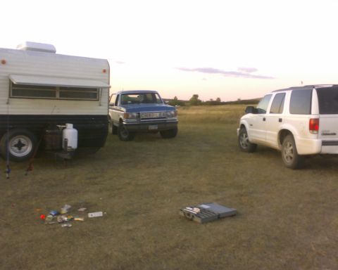 1989 Ford Bronco - A blue 1987 Ford Bronco is parked in a grassy field next to a trailer and a white SUV.