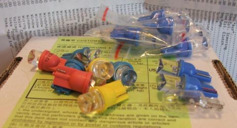 1985 Ford LTD Crown Victoria - Various automotive light bulbs are shown, some in plastic packaging, on top of a customs declaration form.