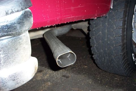 1995 Ford Bronco - Close-up view of the exhaust pipe and rear bumper of a red vehicle.