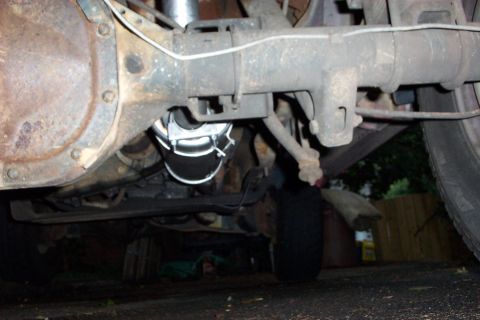 1995 Ford Bronco - Close-up of the rear axle and suspension components of a vehicle, showing the differential and part of the exhaust.
