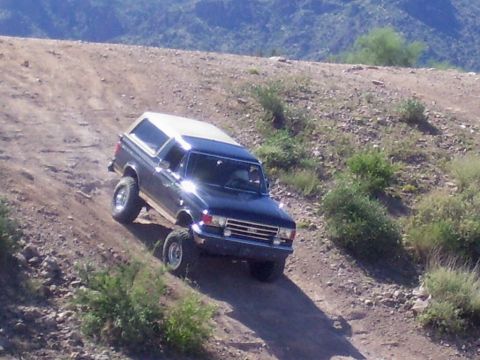 1991 Ford Bronco - This Ford Bronco is navigating a steep, dusty trail in a mountainous, arid region.