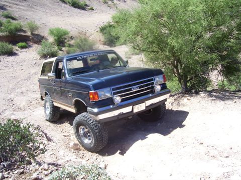 1991 Ford Bronco - This 1991 Ford Bronco is navigating a challenging off-road path in a dry, arid environment.