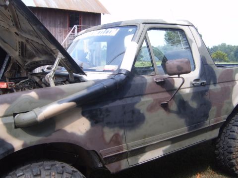 1988 Ford Bronco - A camouflage-painted pickup truck is shown with its hood up and a snorkel installed.