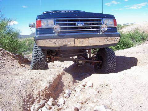 1991 Ford Bronco - A lifted 1992 Ford Bronco navigates a challenging dirt path under a clear blue sky.