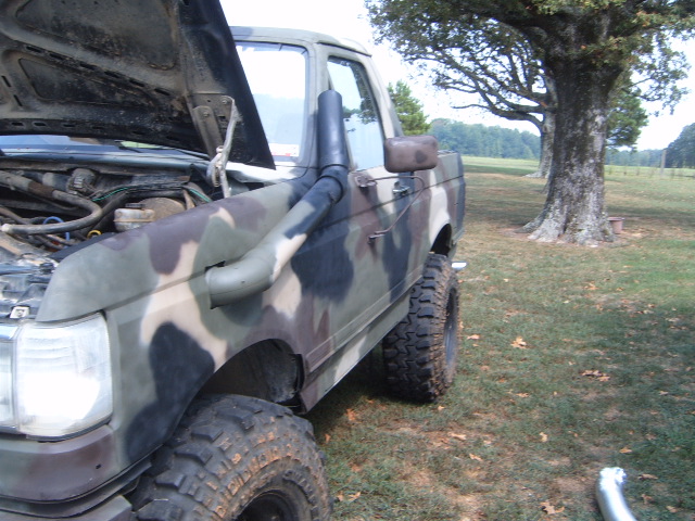 Camo-painted lifted Ford Bronco with hood up and fender-mounted snorkel on mud tires