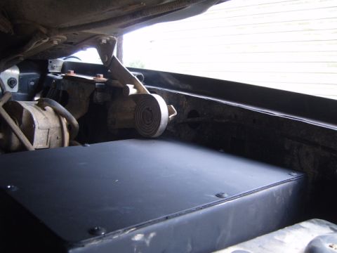 1988 Ford Bronco - Close-up of engine bay components, including a black cover and mechanical linkages.