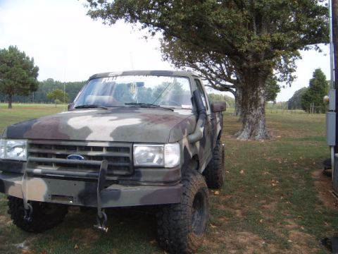 1988 Ford Bronco - This camouflage Ford truck features a snorkel and a heavy-duty bull bar, suggesting off-road modifications.