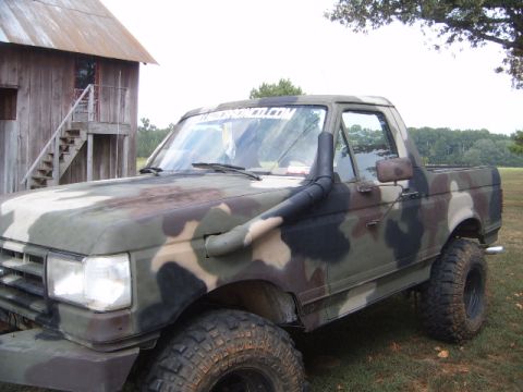 1988 Ford Bronco - Camouflaged 1988 Ford Bronco equipped with a snorkel intake, parked outdoors.