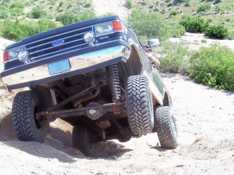 1991 Ford Bronco - This lifted 1991 Ford Bronco navigates a rocky, off-road trail with its front wheels angled upwards.