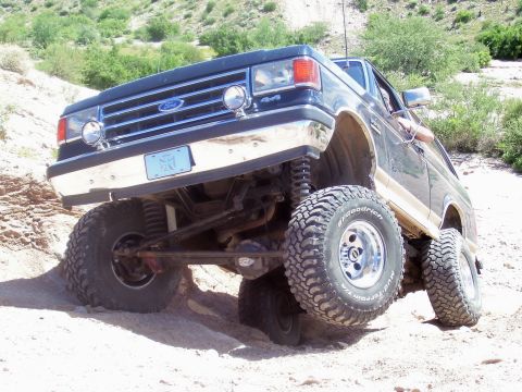 1991 Ford Bronco - Modified Ford Bronco navigating rough terrain on a sunny day.