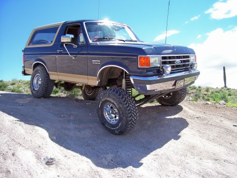 1991 Ford Bronco - This lifted 1991 Ford Bronco is shown off-road under a bright blue sky.