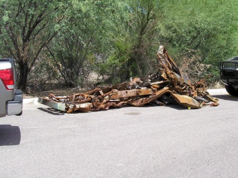 1991 Ford Bronco - This heavily damaged and rusted vehicle chassis is piled up on the side of a road.