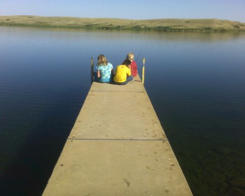 1989 Ford Bronco - Three people enjoy a day of fishing from a concrete dock extending into a calm lake.