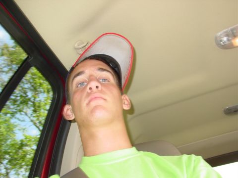 1998 Ford Mustang - A young man with a cap on backwards looks out from inside a vehicle, with trees visible through the window.