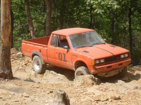1995 Ford Bronco - An orange pickup truck navigates a challenging, rocky off-road course.