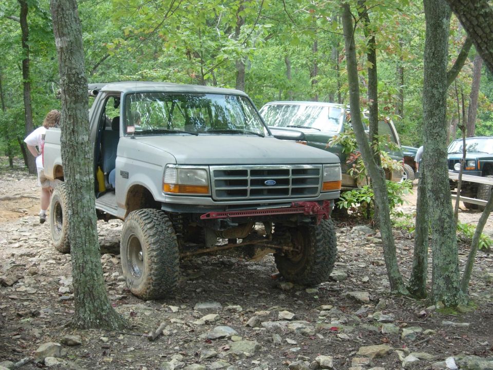 Gray 1995 Ford Bronco with lifted suspension and off-road tires parked in a wooded area