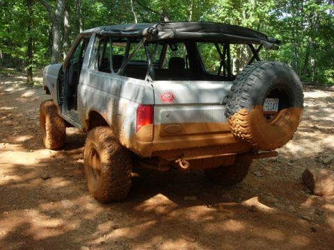 1995 Ford Bronco - This heavily modified Ford Bronco is shown off-road, covered in mud with its soft top removed.