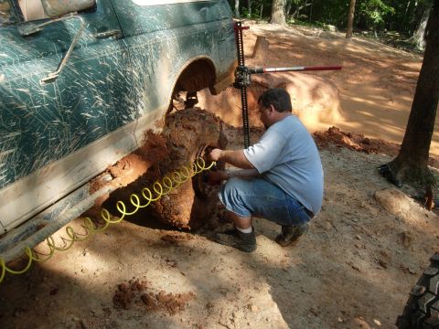 1995 Ford Bronco - A man attempts to free a mud-covered 1992 Ford Bronco with a jack.