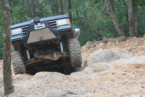 1990 Ford Bronco - A green Ford Bronco navigates a challenging rocky trail.