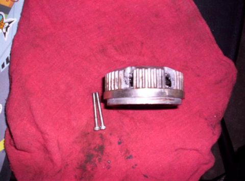 1995 Ford Bronco - A close-up view of a metal component and two screws resting on a red fabric surface.