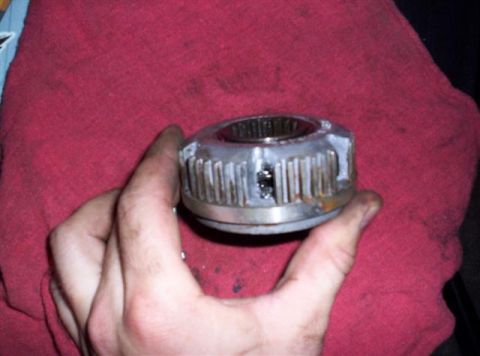 1995 Ford Bronco - A U-joint part is held for inspection, revealing wear and damage on its metal surface.