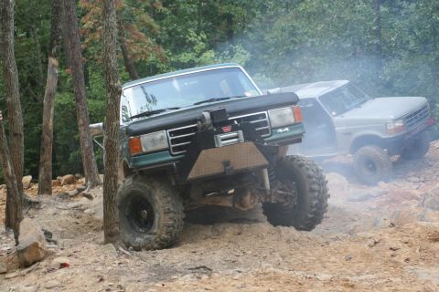 1990 Ford Bronco - A modified 1990 Ford Bronco navigates a rocky trail, with another Bronco following behind.