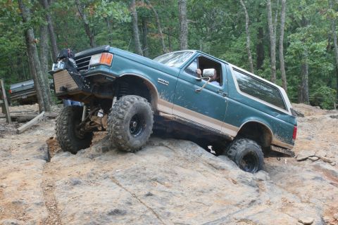 1990 Ford Bronco - A modified Ford Bronco navigates a challenging rocky trail with another vehicle visible in the background.