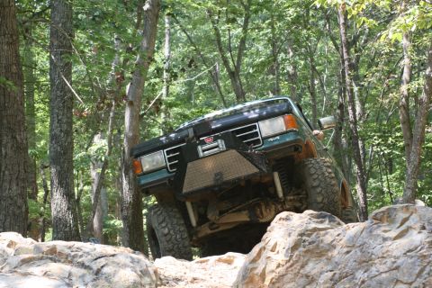 1990 Ford Bronco - This truck is navigating a rocky trail through a dense forest.