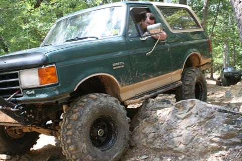 1990 Ford Bronco - A green Ford Bronco tackles a rocky trail with a second vehicle in the background.