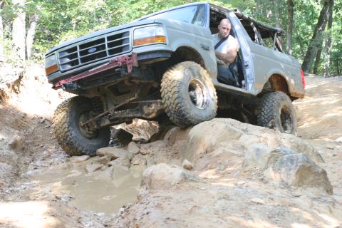 1990 Ford Bronco - Ford Bronco tackling a challenging off-road course on rocks and mud.