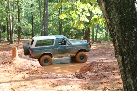 1990 Ford Bronco - This 1990 Ford Bronco navigates a challenging mud pit on a wooded trail.