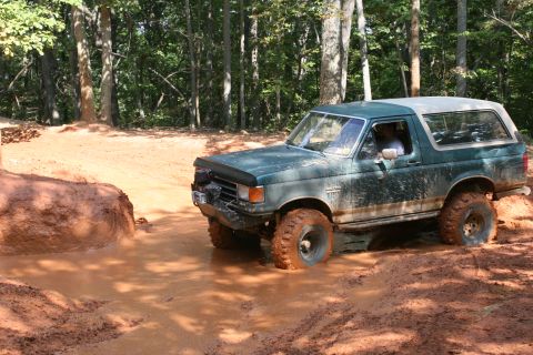 1990 Ford Bronco - Ford Bronco tackling a challenging mud pit during an off-road excursion.
