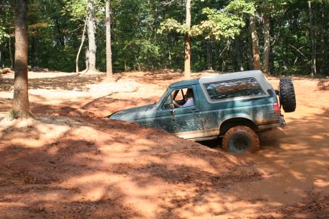 1990 Ford Bronco - This Ford Bronco is deep in the mud, with only its tires and lower body visible.
