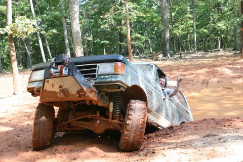 1990 Ford Bronco - A driver gives a rock-on hand sign while his 1990 Ford Bronco is stuck deep in mud.