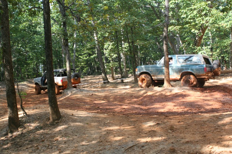 Teal Ford Bronco off-roading on a dirt trail with another vehicle behind it