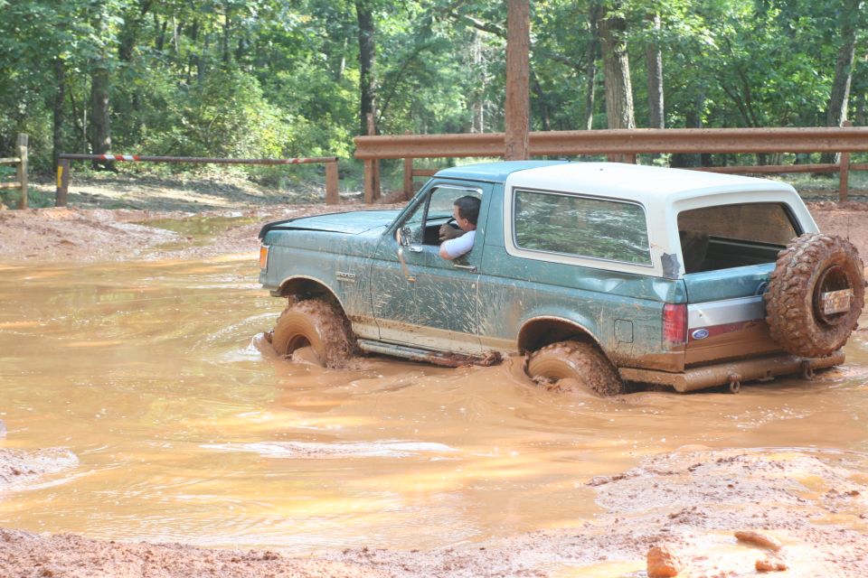 Teal Ford Bronco stuck in mud, rear-mounted spare tire visible