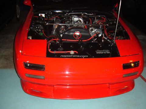 1991 Ford Probe - The engine bay of a red car is shown with custom modifications and visible text on a black cover.