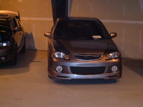 1991 Ford Probe - Two cars are parked indoors, one with its hood open and a large spoiler.