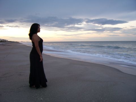 1994 Ford Probe - A woman stands on a sandy beach, looking out at the ocean as the sun sets.